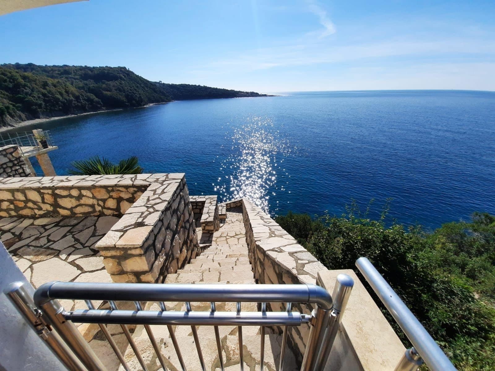 Каменная лестница и терраса виллы в Добра Вода, Черногория, с панорамным видом на Адриатическое море и горы.