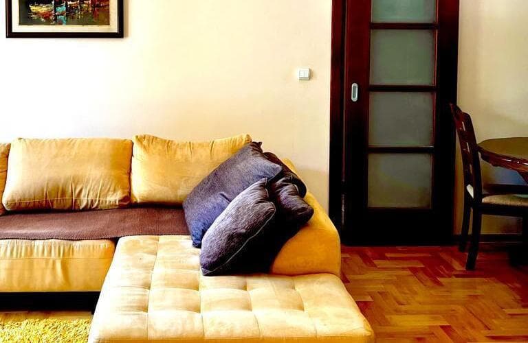 Интерьер гостиной с бежевым угловым диваном и паркетом в квартире, Кумбор, Черногория.