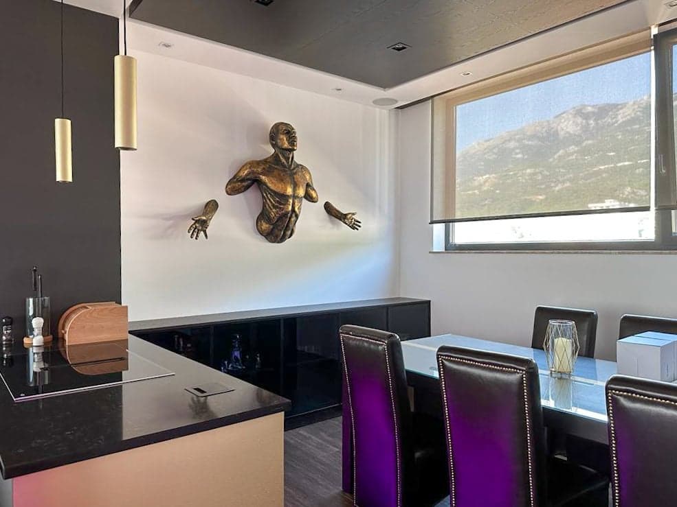 Дизайнерская столовая в пентхаусе в Бечичи, Черногория: стильная мебель, декор на стене и вид на горы из окна.