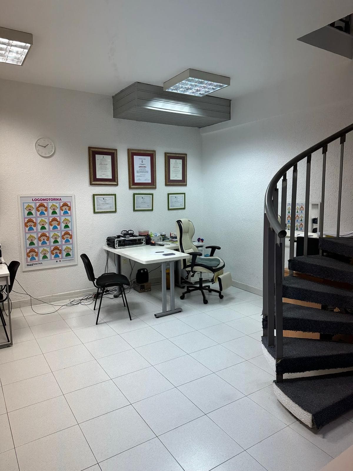 Коммерческое помещение в Баре, Черногория: светлый кабинет с винтовой лестницей, рабочим столом и офисной мебелью.