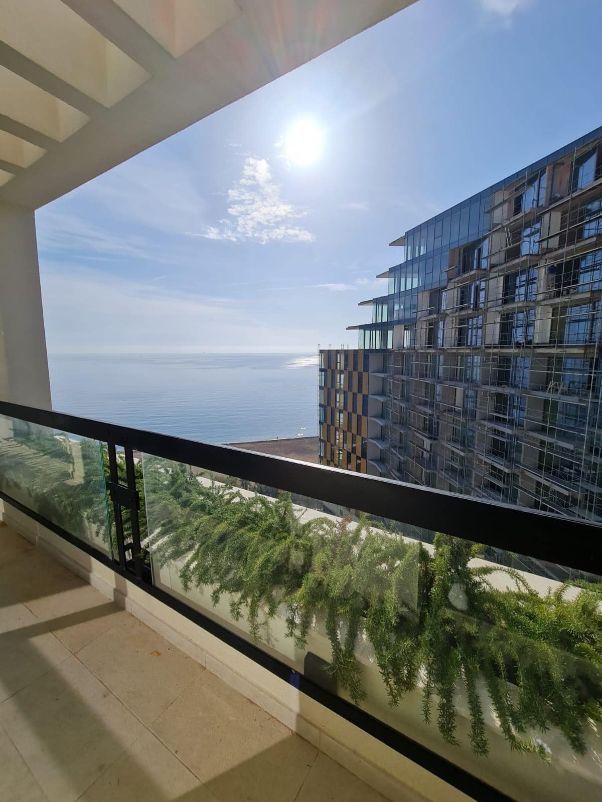 Вид на море и пляж с балкона апартаментов в Рафаиловичи, Черногория: современное здание и озеленение террасы.
