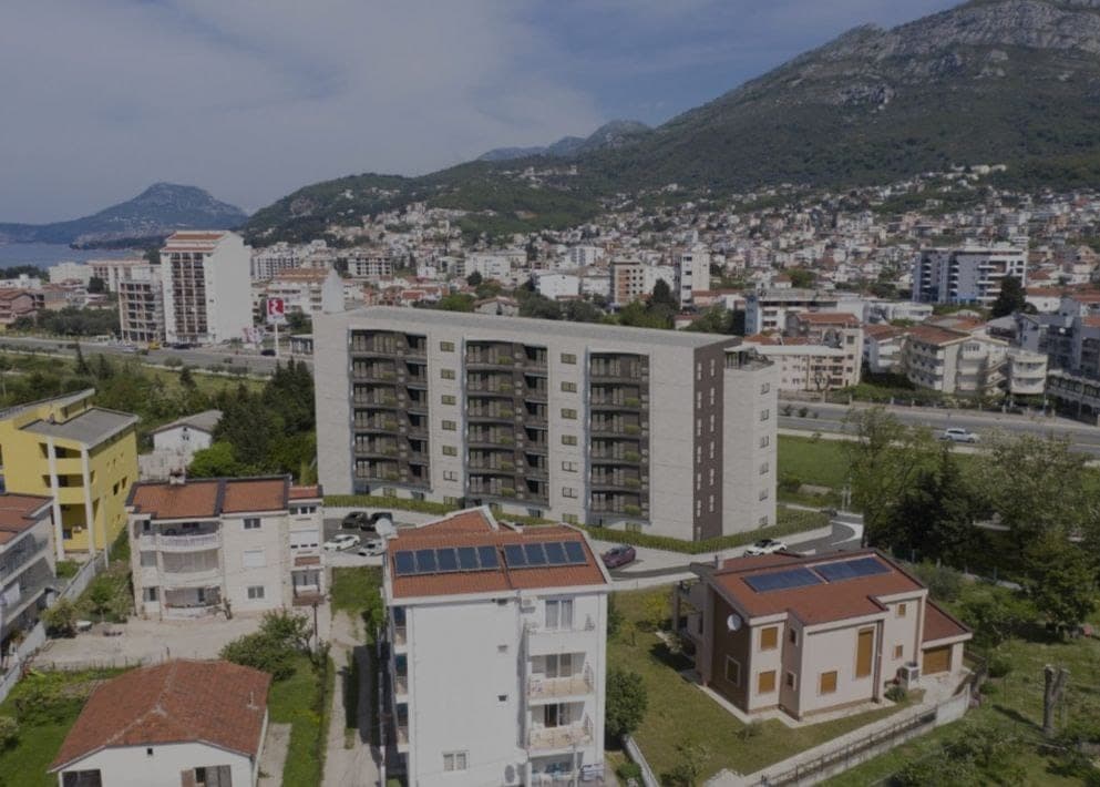 Вид с воздуха на современный жилой комплекс в городе Бар, Черногория, на фоне гор и городской застройки.