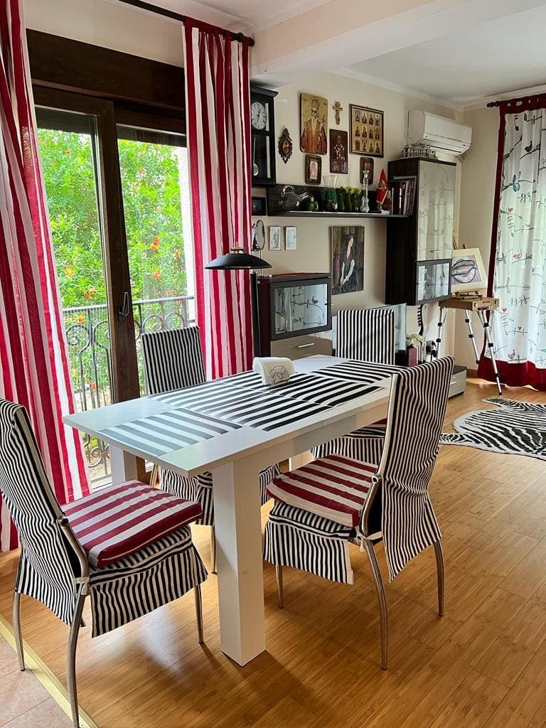 Обеденная зона в квартире в Будве, Черногория: стол, стулья в полоску, выход на балкон с видом на зелень и декор.