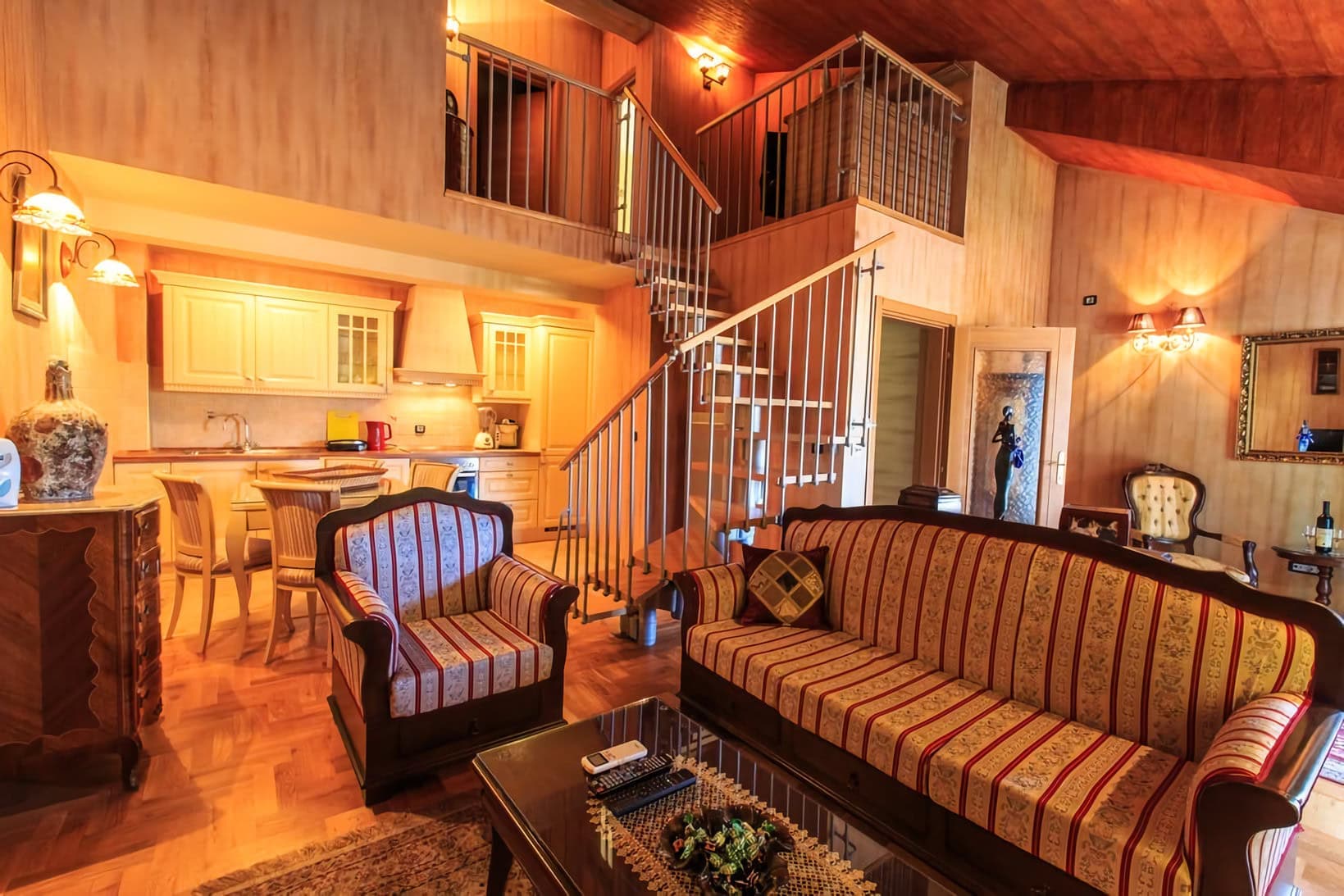 Интерьер двухуровневой квартиры в Которе, Черногория: гостиная с винтажной мебелью и лестницей на второй этаж.