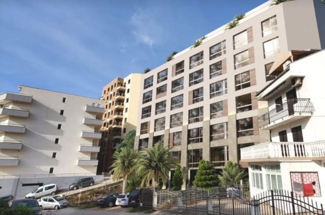 Современный жилой комплекс с панорамными окнами в Бечичи, Черногория: вид на фасад здания и прилегающую территорию.