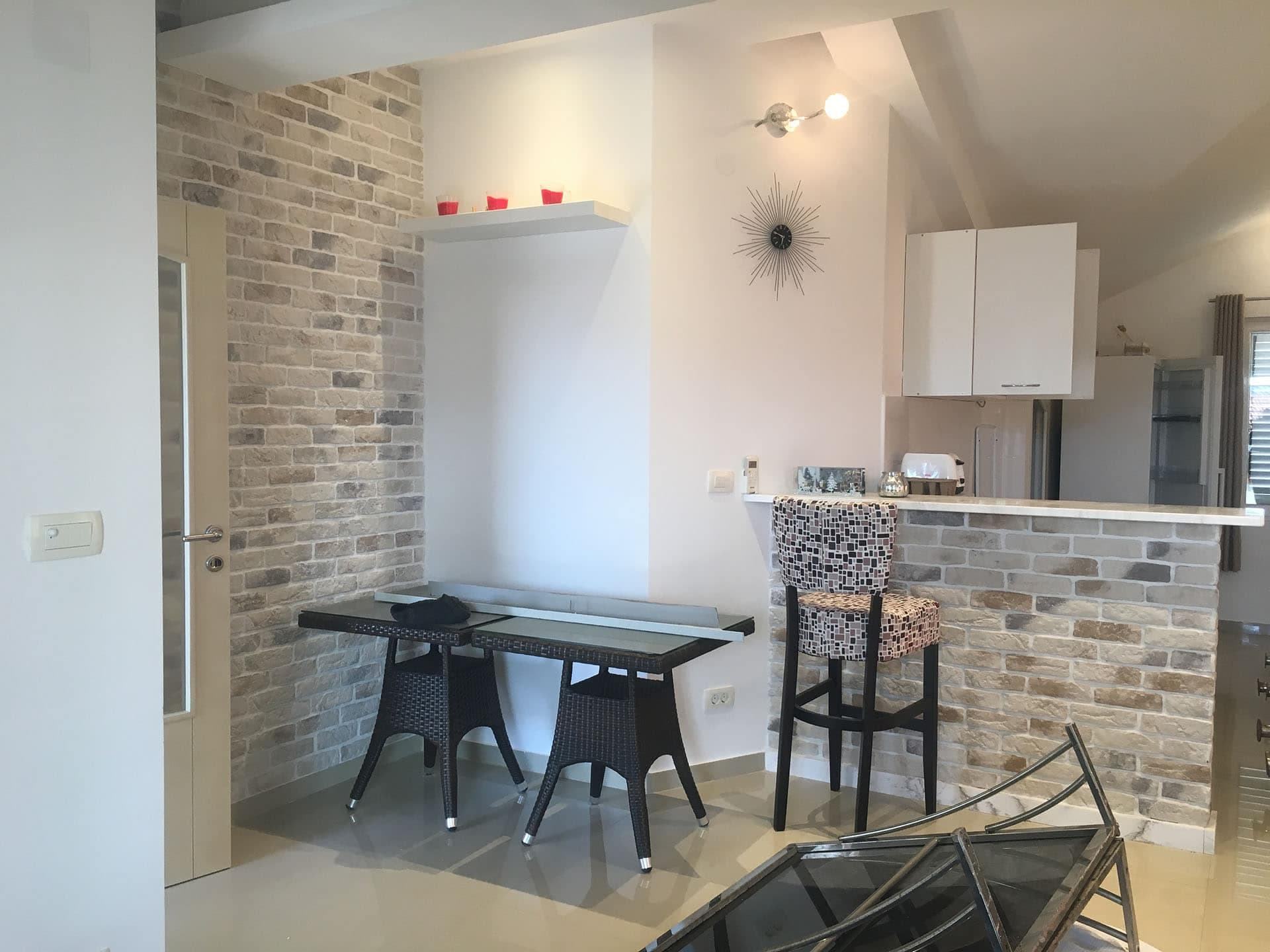 Интерьер кухни-гостиной с кирпичной отделкой и барной стойкой в квартире в Тивате, Черногория.