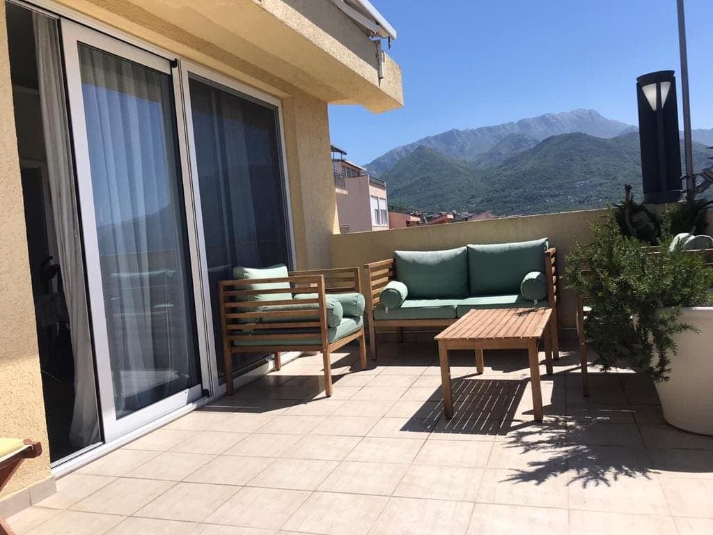 Терраса виллы в Шушани, Черногория: деревянная мебель с мягкими подушками и панорамный вид на горы.