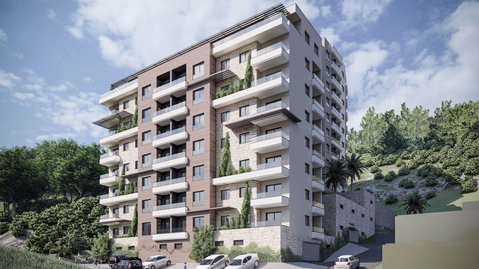 Современный жилой комплекс с балконами и каменной отделкой фасада в окружении гор и зелени, Черногория.