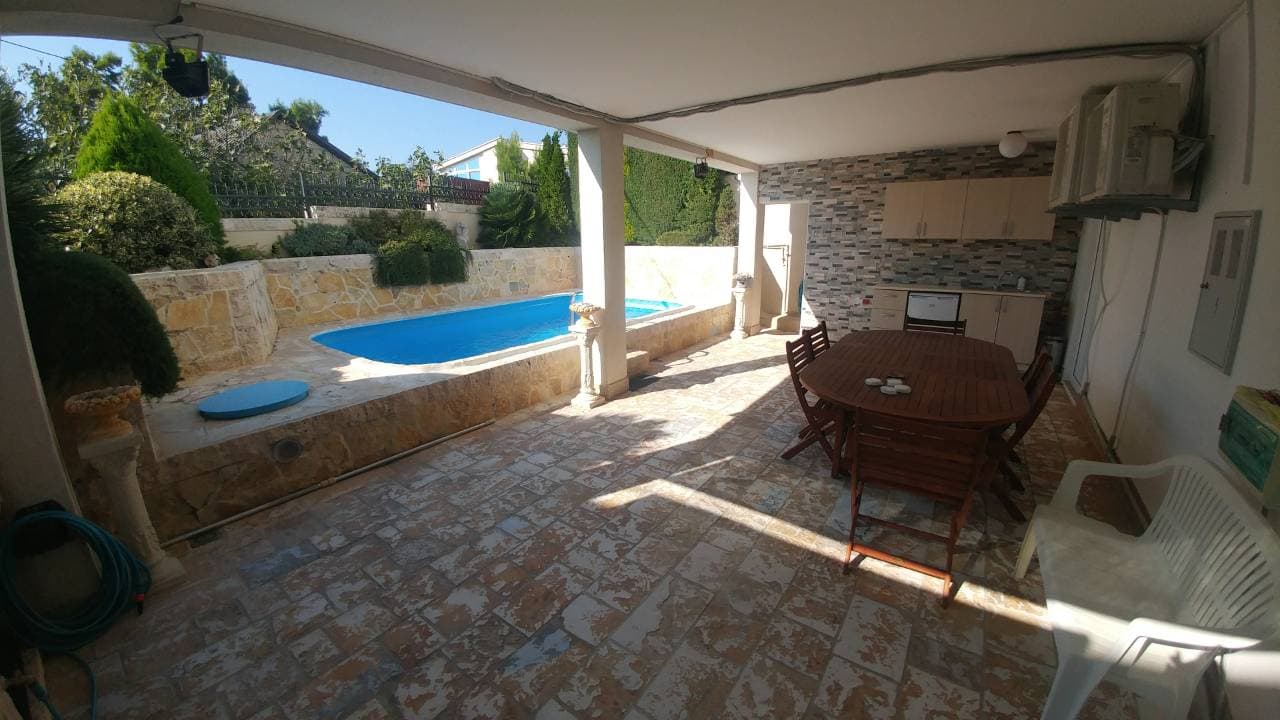 Крытая терраса с обеденной зоной и бассейном у дома в Ратаце, Черногория: каменная отделка, летняя кухня и сад.