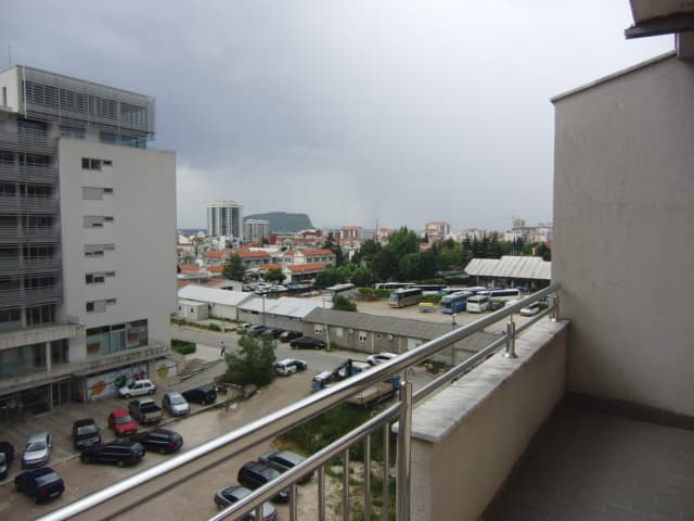 Вид с балкона квартиры в Будве, Черногория: панорама города, парковка и жилые дома в пешей доступности.