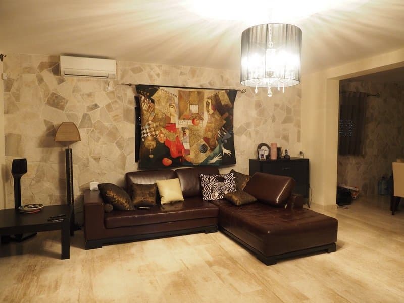 Гостиная виллы в Столиве, Черногория: кожаный угловой диван, отделка стен натуральным камнем и стильная люстра.