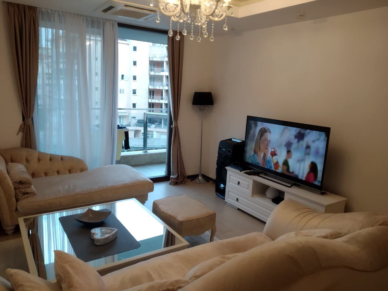 Светлая гостиная с бежевой мягкой мебелью и выходом на балкон в квартире в Будве, Черногория.