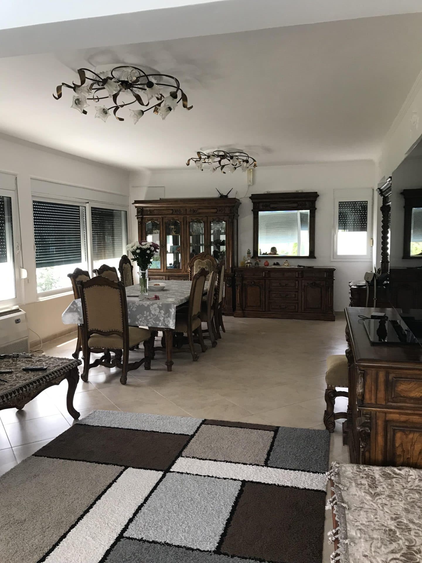 Просторная обеденная зона с классической деревянной мебелью в доме, город Бар, Черногория. Светлая гостиная с ковром.