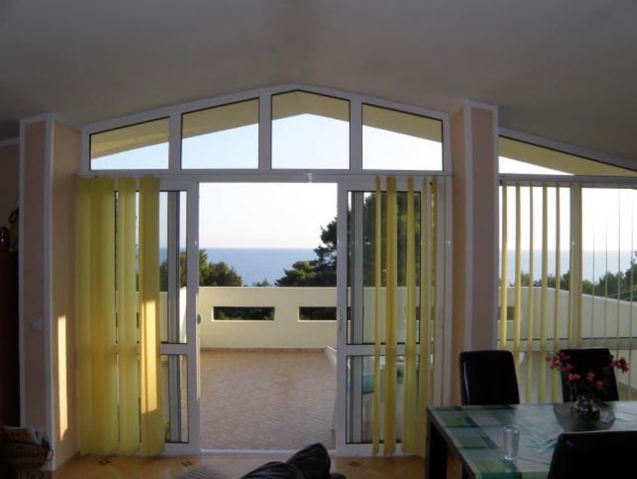 Гостиная с панорамными окнами и выходом на террасу с видом на море в доме, город Бар, Черногория.