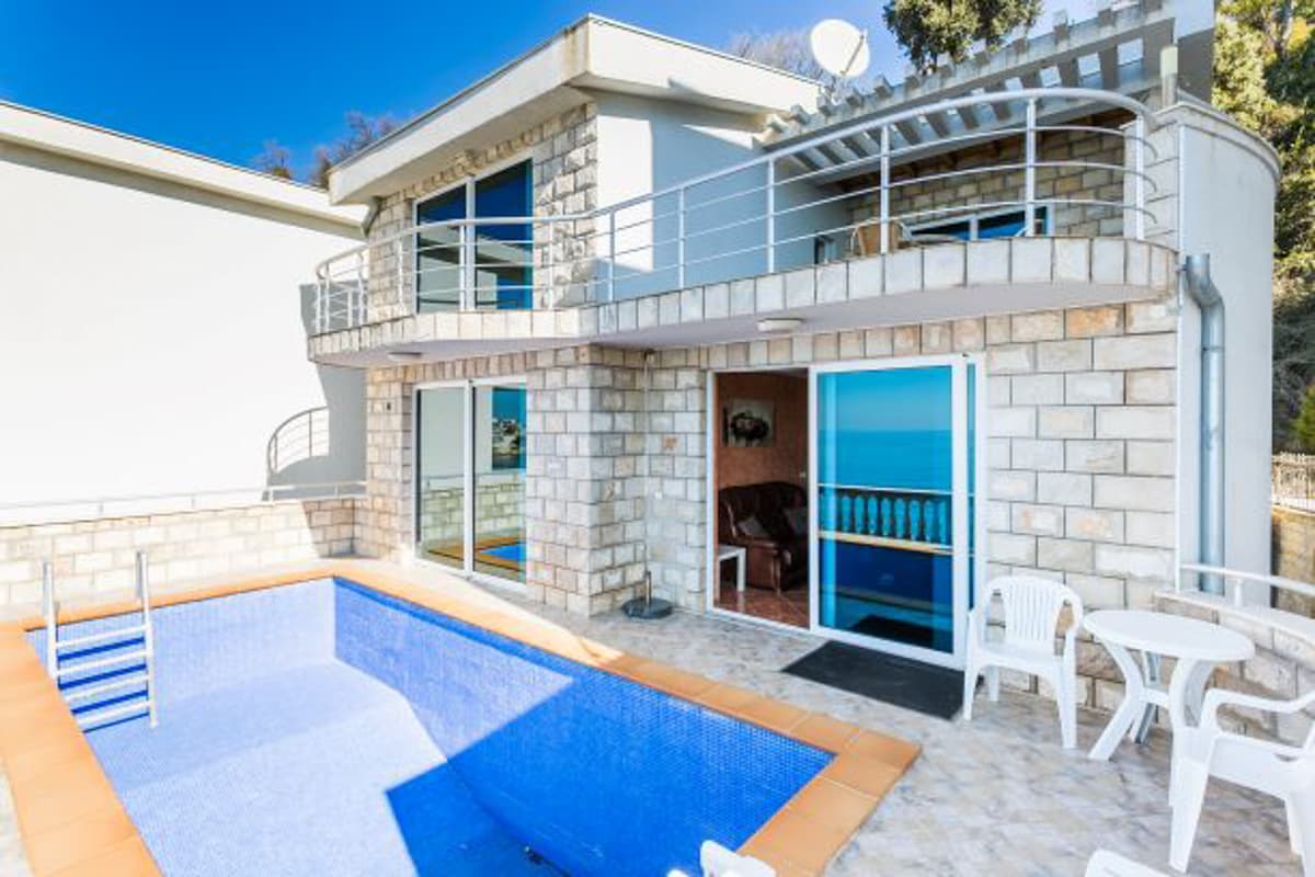 Двухэтажный дом с бассейном и видом на море в поселке Круче, Черногория: каменная отделка фасада и терраса.