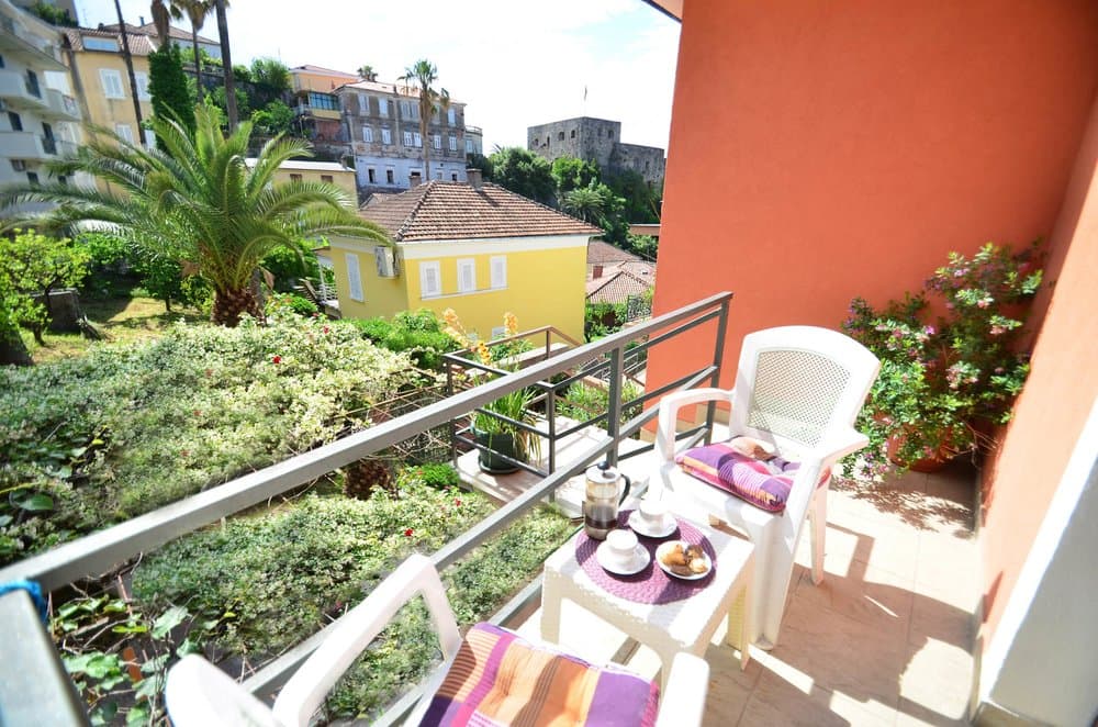 Балкон с видом на старый город и сад в доме Герцег-Нови, Черногория: пластиковая мебель, уютная зона отдыха.