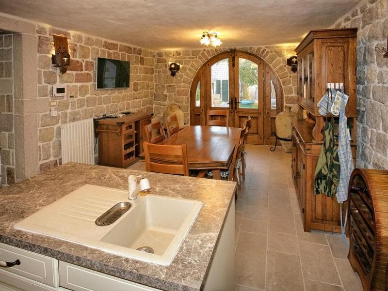 Интерьер кухни-столовой с каменными стенами и деревянной мебелью на вилле в Режевичи, Черногория.