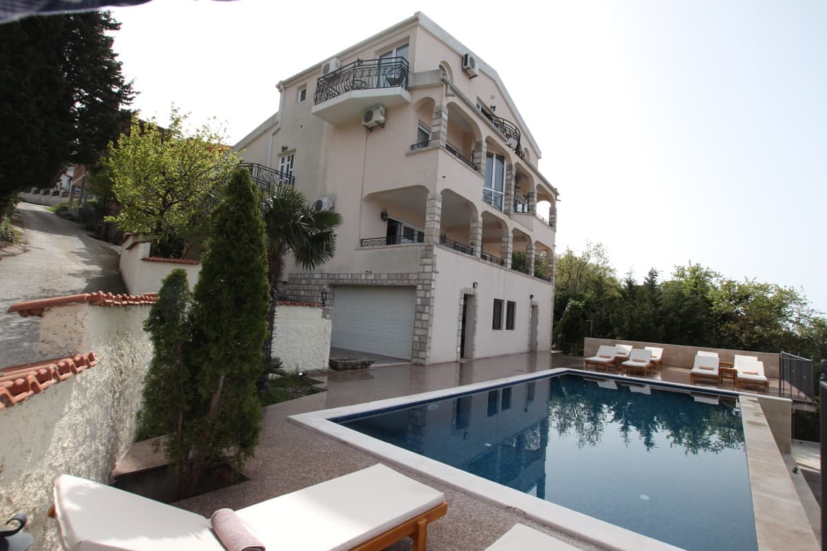 Трехэтажный дом с бассейном и шезлонгами в Сутоморе, Черногория: вид на виллу с террасами и гаражом.