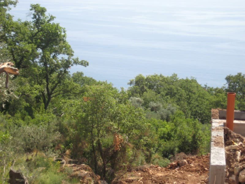 Вид на море с земельного участка под строительство в Режевичи, Черногория: панорама побережья и зеленый сад.