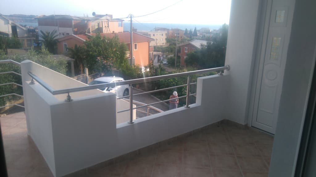 Терраса дома в Шушани, Черногория: вид на море, современное ограждение из нержавеющей стали и плиточный пол.