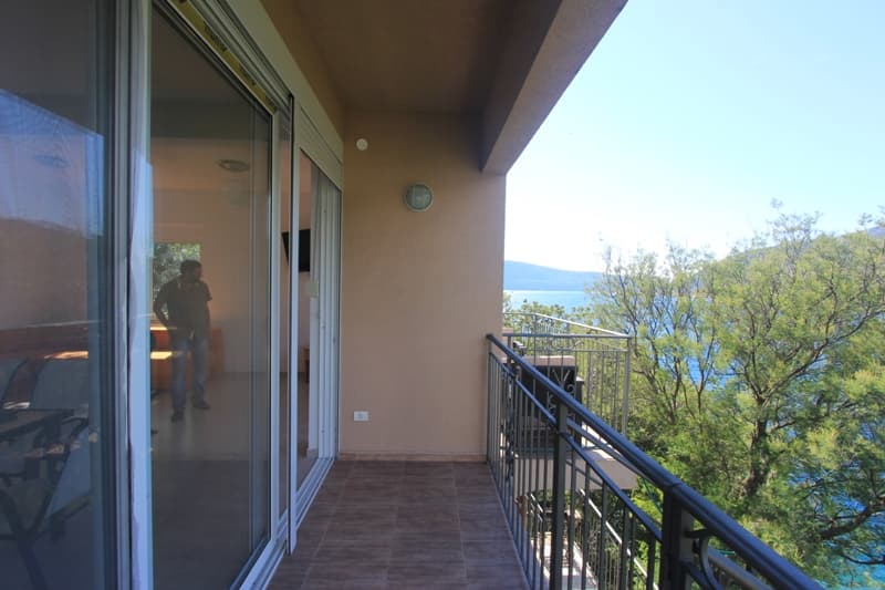 Балкон виллы в Лепетане, Черногория: панорамный вид на море, плиточный пол, раздвижные стеклянные двери и ограждение.