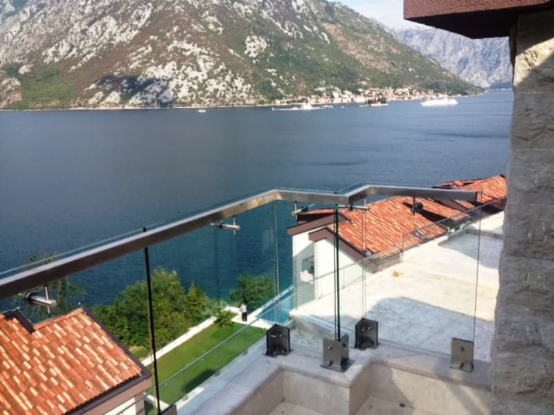 Вид с террасы со стеклянным ограждением на Которский залив и горы в жилом комплексе Костаница, Черногория.