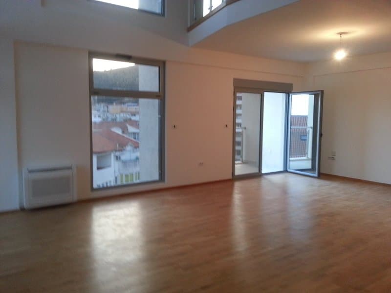 Просторная гостиная с панорамными окнами и выходом на балкон в квартире, Будва, Черногория. Светлый интерьер, паркет.