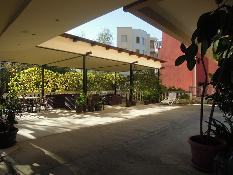 Крытая терраса с плетеной мебелью и растениями в доме в Бечичи, Черногория: зона отдыха на открытом воздухе.