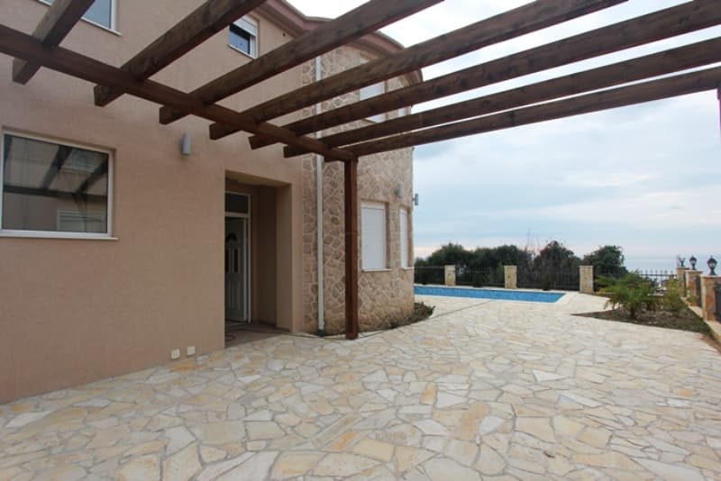 Терраса с деревянной перголой и бассейном у дома в Добрых Водах, Черногория: каменная отделка фасада и вид на море.