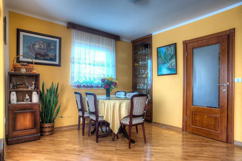 Уютная обеденная зона в отеле Бечичи, Черногория: деревянная мебель, желтые стены, витрина для посуды и паркет.