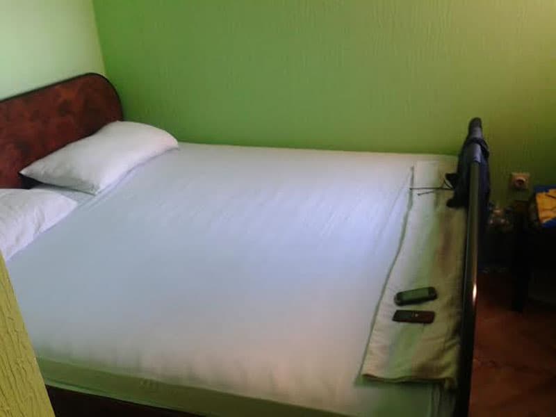 Спальня с двуспальной кроватью и зелеными стенами в апартаментах, Петровац, Черногория.