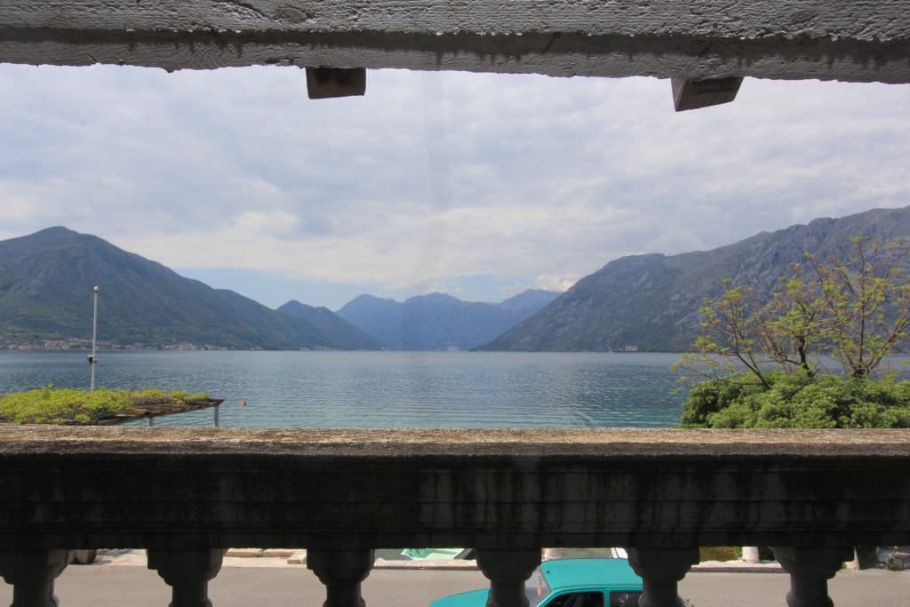 Панорамный вид на Которский залив и горы с каменного балкона дома в Доброте, Черногория.