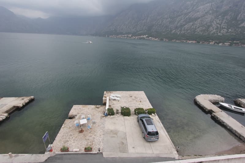 Вид на частный причал с зоной отдыха и парковкой у моря, вилла в Прчани, Которский залив, Черногория.