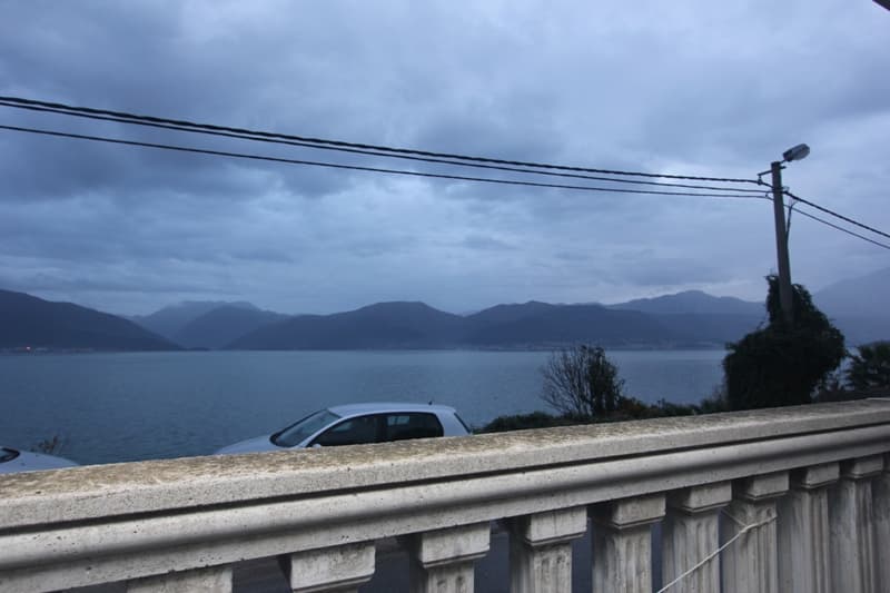 Вид с балкона с балюстрадой на море и горы в Крашичи, Черногория. Панорама залива в пасмурную погоду.