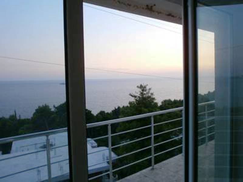Вид на море и закат с балкона мини-отеля в Шушани, Черногория: панорамное остекление и современное ограждение.