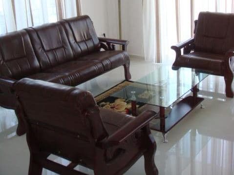 Гостиная с кожаной мебелью и стеклянным столом в квартире в Столиве, Черногория: светлый интерьер с панорамными окнами.