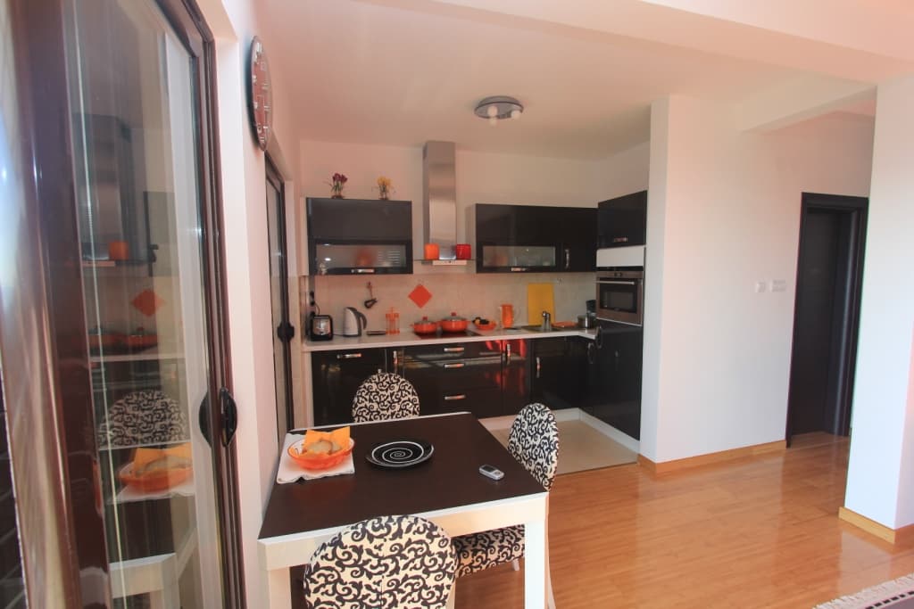 Современная кухня-столовая с черным гарнитуром в квартире, Рафаиловичи, Черногория: обеденная зона и панорамное окно.