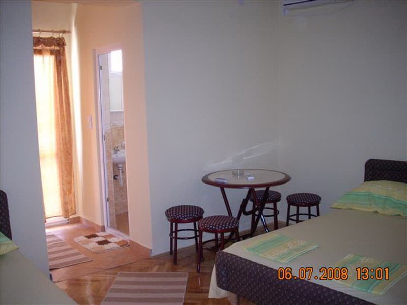 Интерьер спальни с кроватью, обеденным столом и выходом в санузел в доме на курорте Сутоморе, Черногория.