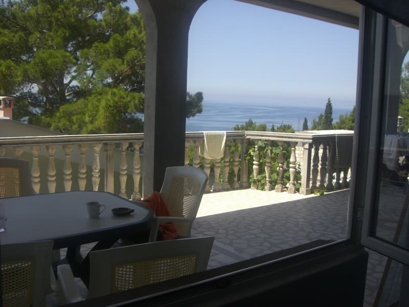 Терраса с балюстрадой и видом на море в доме, Шушань, Черногория: пластиковая мебель, плиточный пол и сосны.