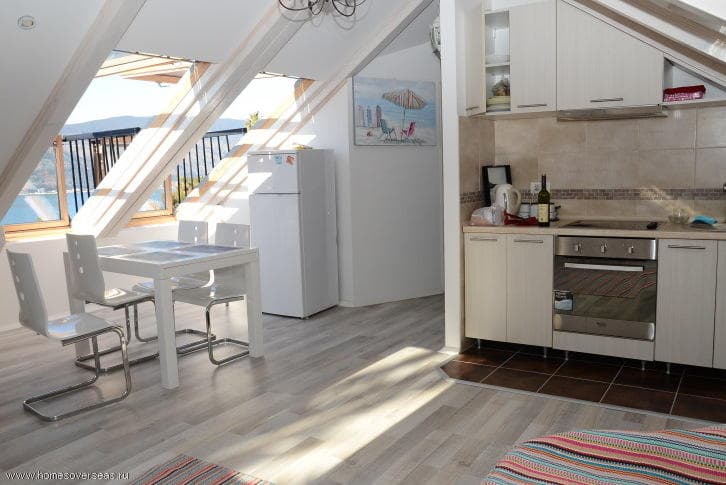 Светлая кухня-столовая в мансардной квартире в Херцег-Нови, Черногория, с видом на море и современной мебелью.