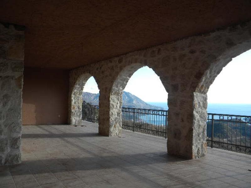 Крытая каменная терраса с арочными проемами и панорамным видом на море и горы в доме, Будва, Черногория.