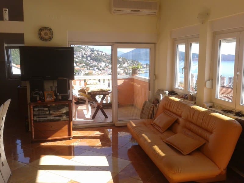 Гостиная с кожаным диваном и выходом на террасу с видом на море в квартире в Игало, Черногория.