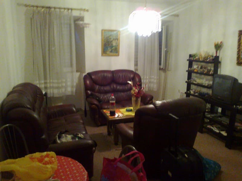 Гостиная в квартире в Будве, Черногория: кожаные диваны, журнальный столик, стеллаж с телевизором и уютное освещение.