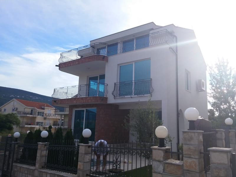 Трехэтажный дом в Дженовичи, Черногория: современный фасад с балконами, панорамными окнами и каменной отделкой.