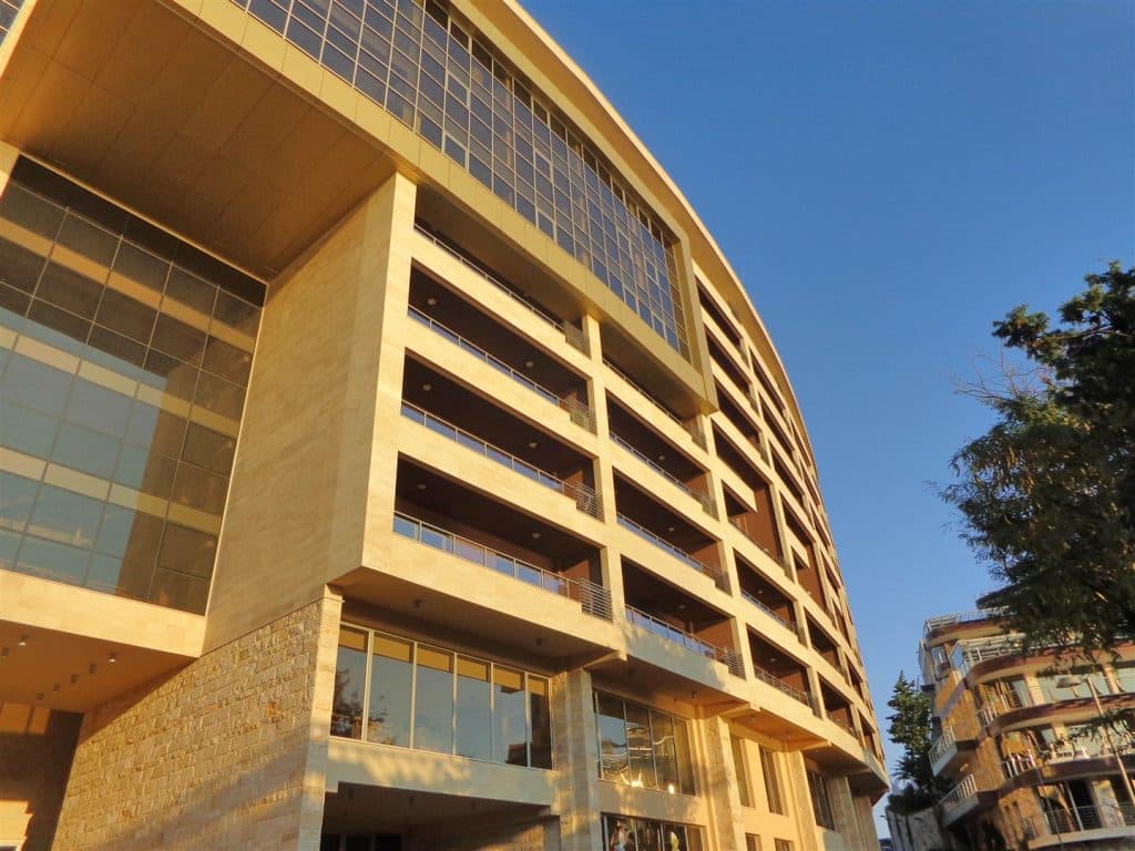 Современный жилой комплекс с панорамными балконами в Бечичи, Черногория: фасад здания с отделкой из камня и стекла.