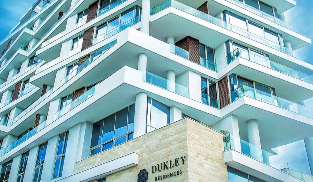 Фасад современного жилого комплекса Dukley Residences в Будве, Черногория: панорамные окна и террасы с остеклением.