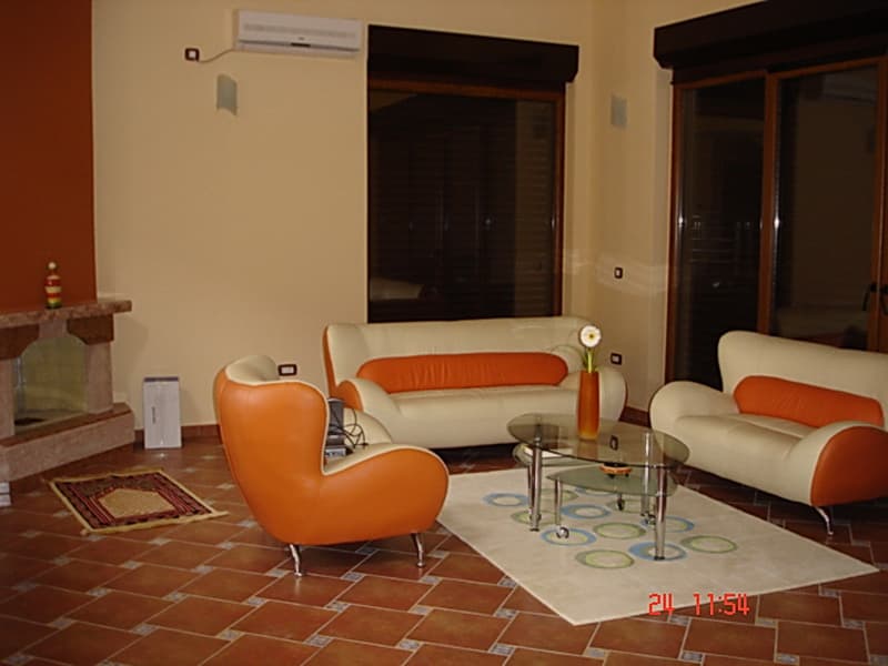 Гостиная виллы в Утехе, Черногория: кожаная мебель, камин, плиточный пол и панорамные окна с выходом на террасу.