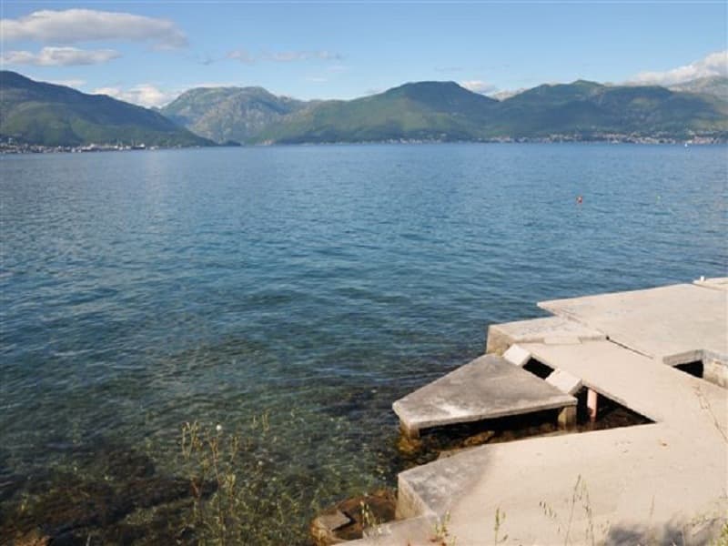 Вид на море и горы с частного участка у воды в Крашичи, Черногория, с бетонным пирсом для спуска в море.