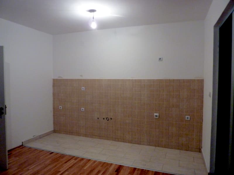 Зона кухни в квартире в Бечичи, Черногория: светлая плитка, фартук из бежевой плитки и выводы под коммуникации.