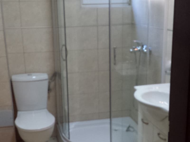 Ванная комната в апартаментах в Пржно, Черногория: душевая кабина, белая сантехника и светлая плитка на стенах.